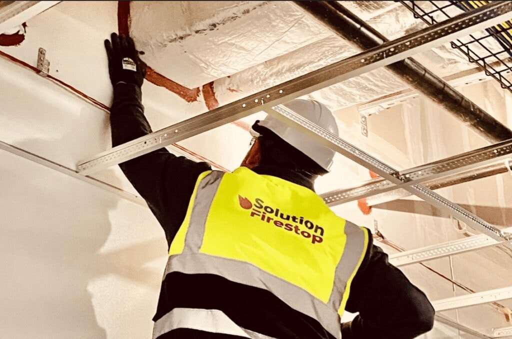 Firestop worker inspecting ceiling with safety vest